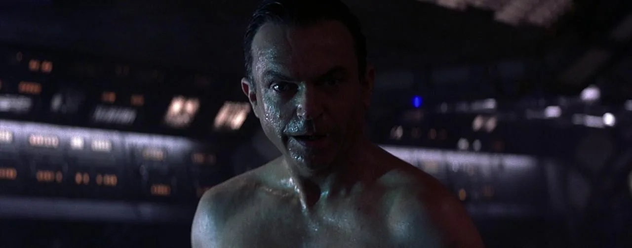 Sam Neill as Dr. Weir standing on the dark bridge of the Event Horizon